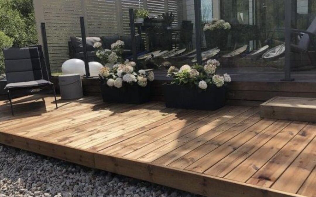 Kuvassa näkyy laadukkaasti rakennettu puuterassi mökkiympäristössä järven rannalla.